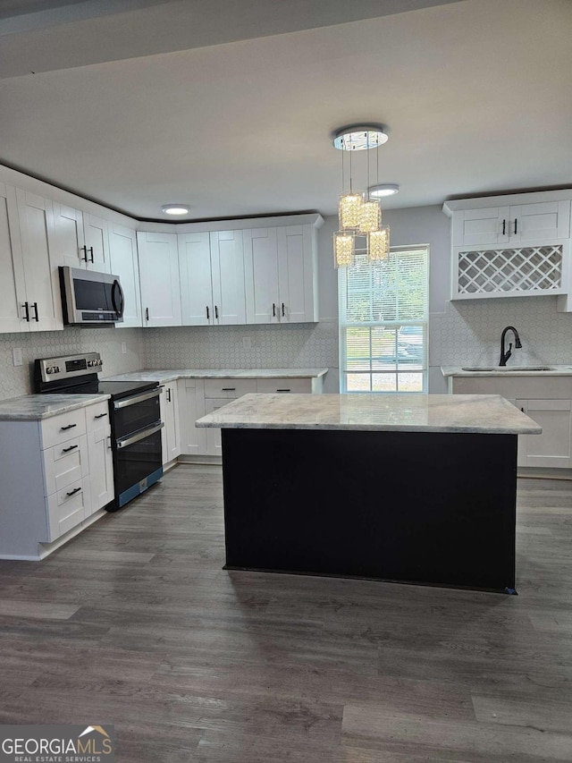 kitchen with hanging light fixtures, a kitchen island, white cabinets, and appliances with stainless steel finishes