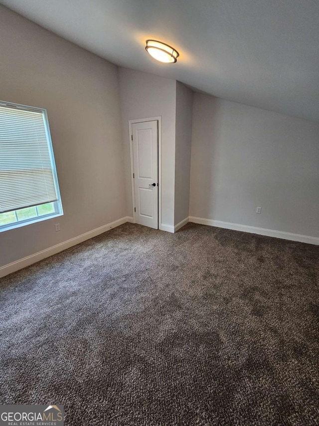 carpeted empty room with lofted ceiling