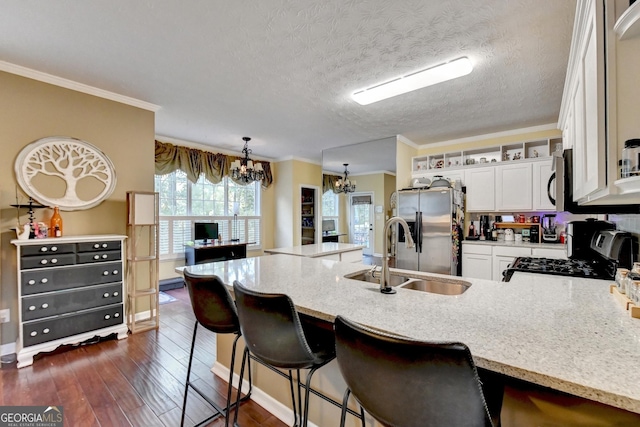 kitchen with a kitchen bar, sink, hanging light fixtures, stainless steel appliances, and white cabinets