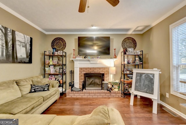 living room with ceiling fan, ornamental molding, a fireplace, and hardwood / wood-style floors