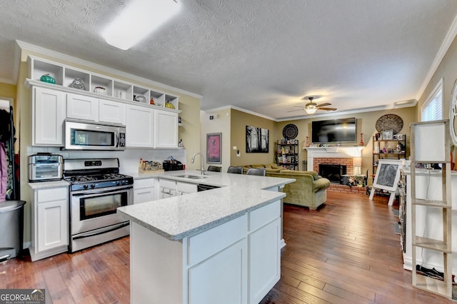 kitchen with sink, dark wood-type flooring, white cabinetry, stainless steel appliances, and kitchen peninsula