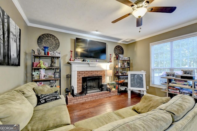 living room with wood-type flooring, a brick fireplace, ceiling fan, and crown molding