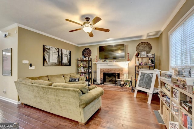 living room with a fireplace, wood-type flooring, ornamental molding, and ceiling fan