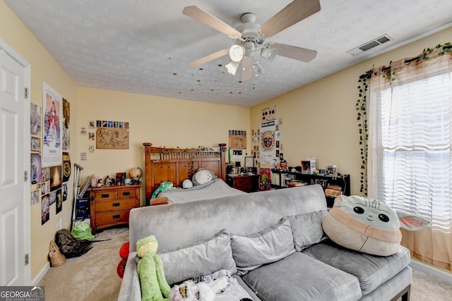 bedroom with ceiling fan, carpet, and a textured ceiling