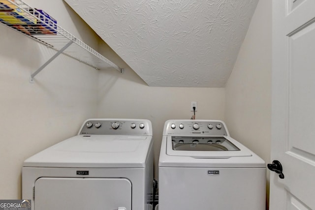 clothes washing area with independent washer and dryer and a textured ceiling