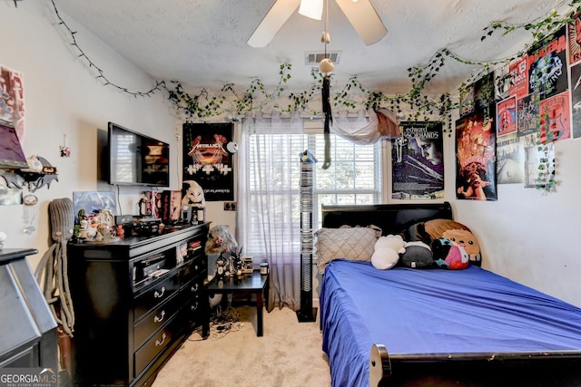 carpeted bedroom featuring ceiling fan and a textured ceiling