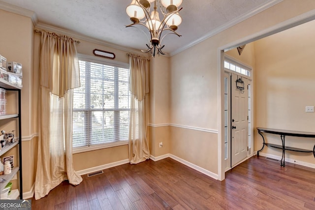 spare room with ornamental molding, wood-type flooring, a notable chandelier, and plenty of natural light