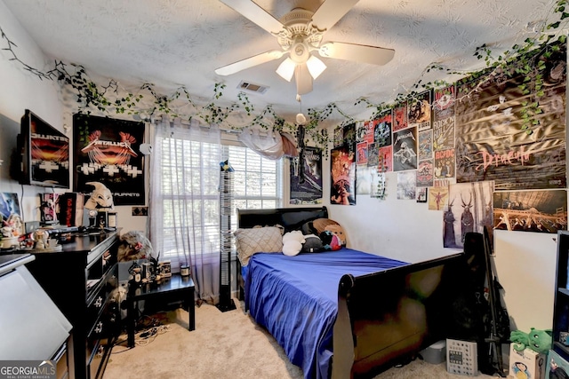 carpeted bedroom featuring ceiling fan and a textured ceiling