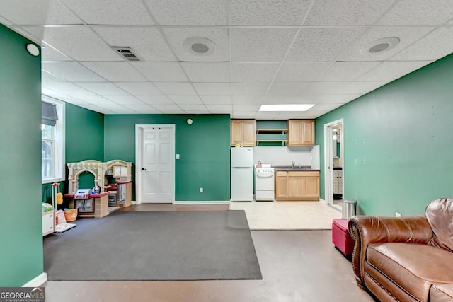 interior space featuring sink, a paneled ceiling, and concrete floors