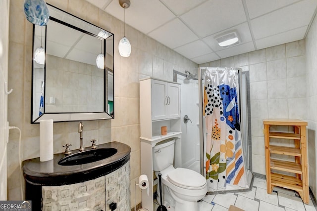 bathroom featuring a shower with shower curtain, tile walls, and a drop ceiling