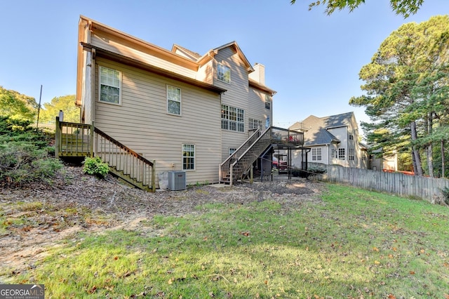 back of house featuring a deck, central AC unit, and a lawn