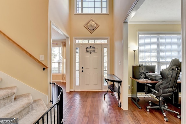 foyer featuring hardwood / wood-style flooring, crown molding, and a high ceiling