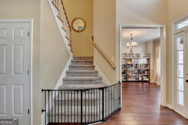 staircase with hardwood / wood-style flooring and a chandelier