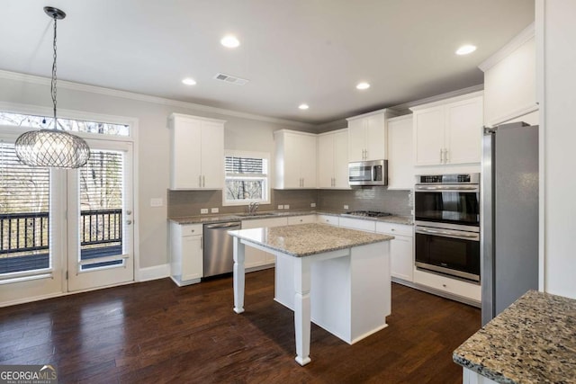 kitchen with a kitchen island, visible vents, appliances with stainless steel finishes, dark wood-style floors, and crown molding