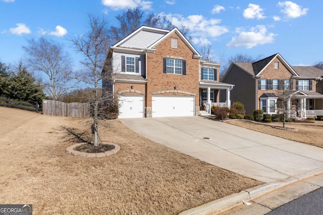 traditional home featuring an attached garage, driveway, fence, and brick siding