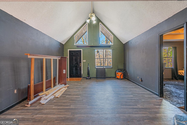 unfurnished living room featuring dark hardwood / wood-style flooring, plenty of natural light, high vaulted ceiling, and a textured ceiling