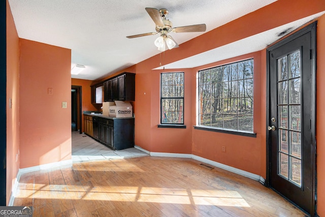 kitchen featuring ceiling fan, dark brown cabinetry, light hardwood / wood-style floors, and a textured ceiling