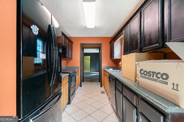 kitchen with sink, light tile patterned floors, dark brown cabinets, black appliances, and a textured ceiling