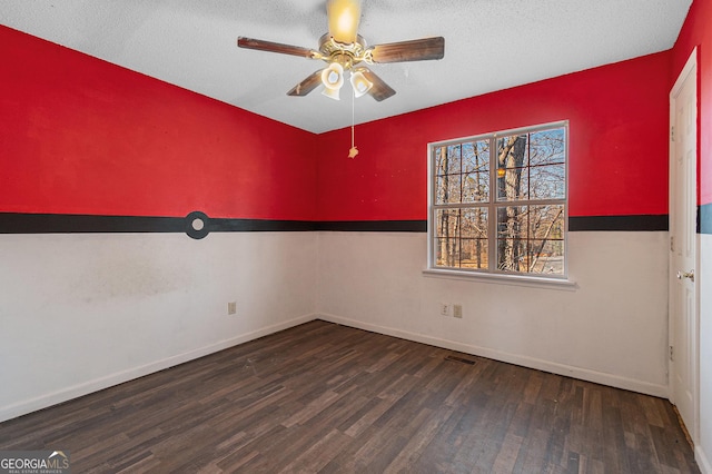 empty room featuring ceiling fan, dark hardwood / wood-style floors, and a textured ceiling