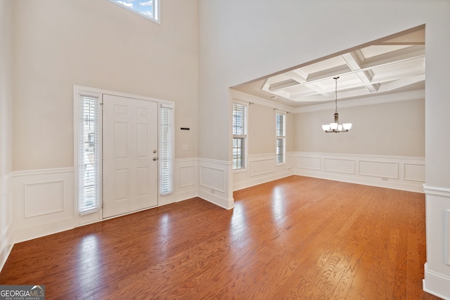 entryway featuring an inviting chandelier, wood-type flooring, coffered ceiling, and beamed ceiling