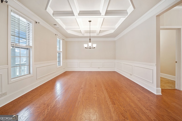 unfurnished dining area featuring an inviting chandelier, coffered ceiling, ornamental molding, beamed ceiling, and light wood-type flooring