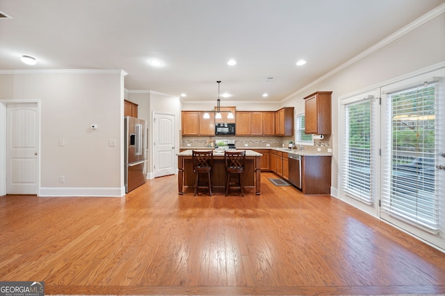 kitchen with hanging light fixtures, stainless steel appliances, a kitchen breakfast bar, tasteful backsplash, and a kitchen island