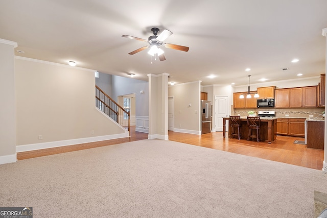 unfurnished living room with crown molding, light carpet, and ceiling fan