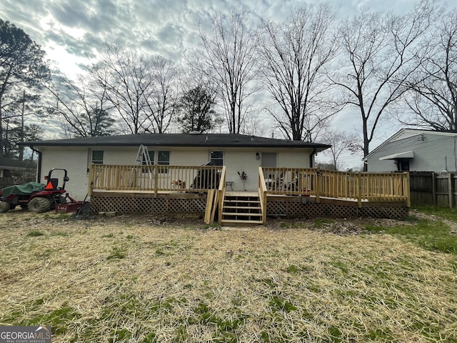 rear view of property with a wooden deck and a lawn