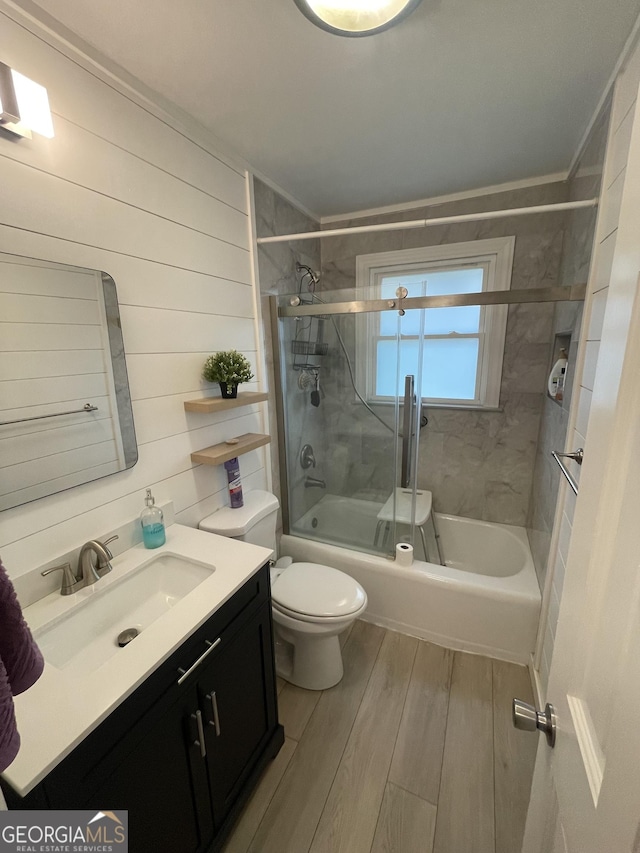 full bathroom with toilet, wood-type flooring, bath / shower combo with glass door, and vanity