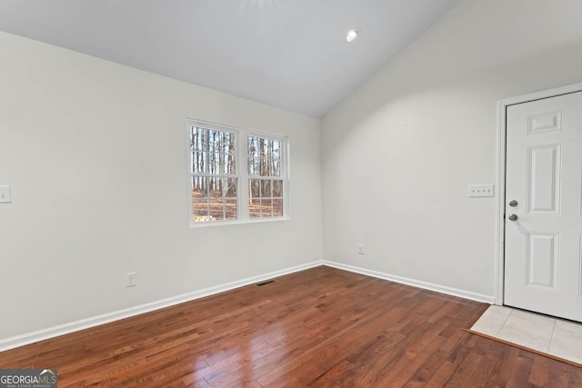 spare room featuring lofted ceiling and hardwood / wood-style flooring