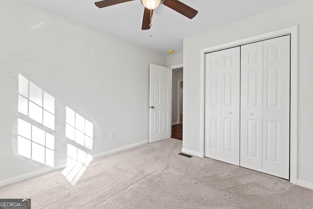 unfurnished bedroom featuring ceiling fan, a closet, and light carpet