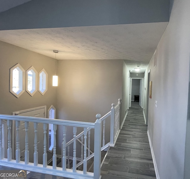 corridor featuring dark wood-type flooring and a textured ceiling