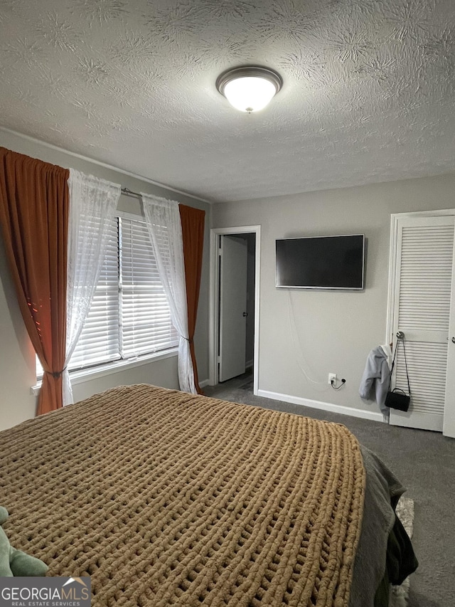 bedroom with a textured ceiling and dark carpet