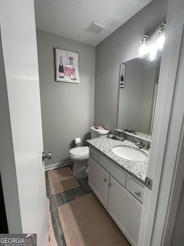 bathroom featuring vanity, a textured ceiling, and toilet