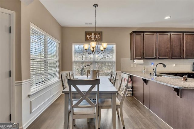 dining space with sink, hardwood / wood-style floors, and a notable chandelier