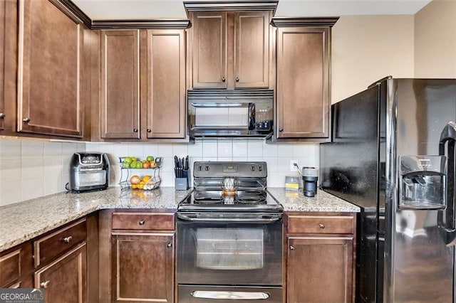 kitchen featuring tasteful backsplash, light stone counters, and black appliances