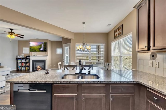 kitchen featuring sink, light stone counters, dark brown cabinets, dishwasher, and backsplash