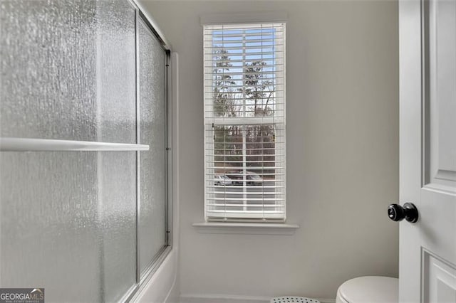 bathroom featuring shower / bath combination with glass door and toilet