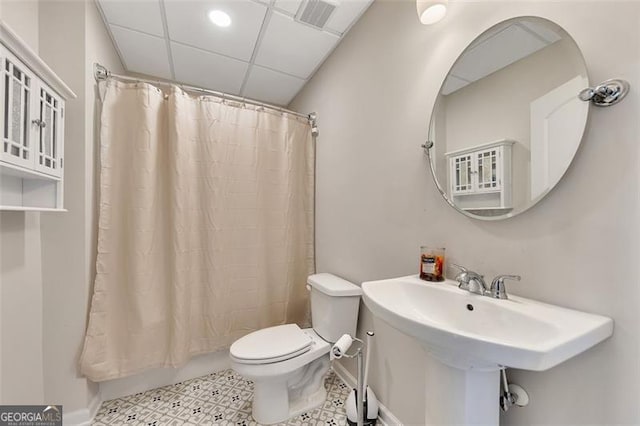 bathroom featuring a paneled ceiling, toilet, and sink