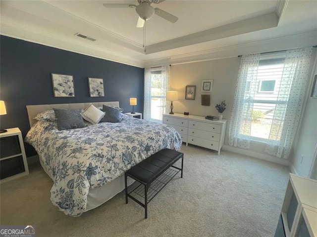 carpeted bedroom featuring multiple windows, ornamental molding, and a tray ceiling