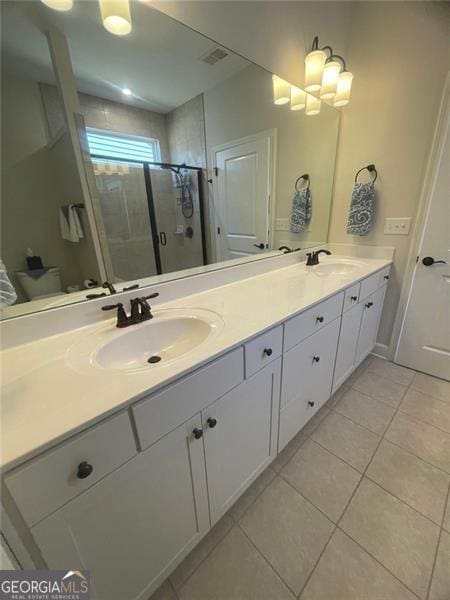 bathroom with tile patterned flooring, vanity, a shower with shower door, and toilet