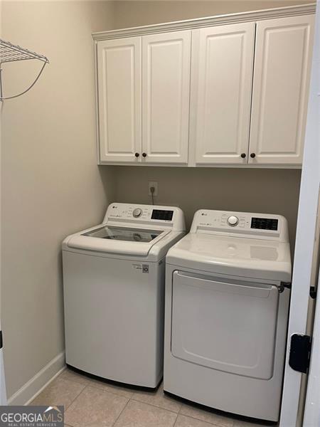 laundry room with cabinets, light tile patterned flooring, and washer and clothes dryer