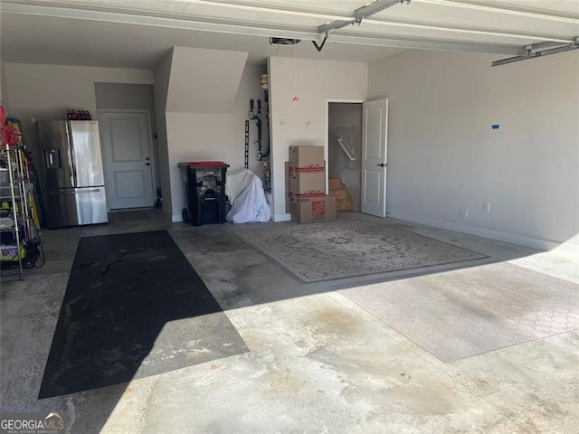 garage with a garage door opener and stainless steel refrigerator with ice dispenser