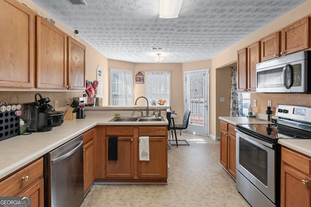 kitchen with stainless steel appliances, sink, a textured ceiling, and kitchen peninsula