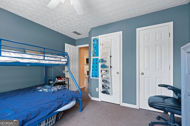 carpeted bedroom featuring ceiling fan and a textured ceiling