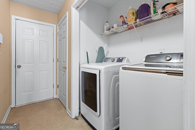 clothes washing area with washer and dryer, light carpet, and a textured ceiling