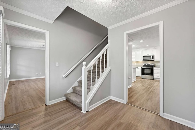 staircase featuring ornamental molding, hardwood / wood-style floors, and a textured ceiling