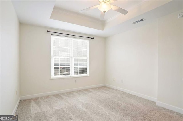 unfurnished room with light carpet, a tray ceiling, and ceiling fan