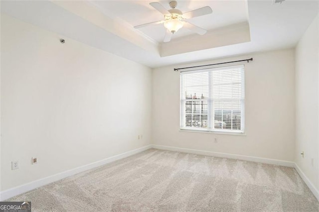 spare room featuring ceiling fan, a tray ceiling, and carpet