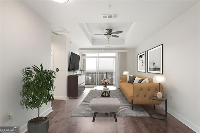 living room featuring ceiling fan, dark hardwood / wood-style flooring, and a tray ceiling